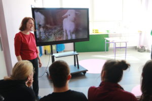 Prowadząca konkurs prezentująca uczniom owieczkę na tablicy multimedialnej.