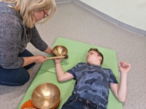 Uczeń podczas masażu dźwiękiem wykonywanego przez nauczycielkę.