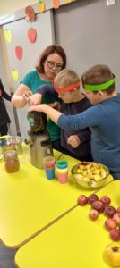 Uczniowei oraz prowadząca robiący sok jabłkowy z użyciem sokowirówki.