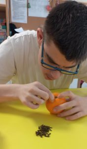 Uczeń dekorujący pomarańczę goździkami