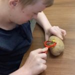 Uczeń obierający ziemniak.