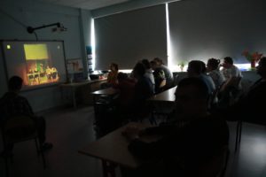 Uczniowie oglądający teatr internatowy na tablicy multimedialnej.