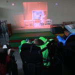 Uczniowie na wózkach oglądający teatr internatowy na tablicy multimedialnej.