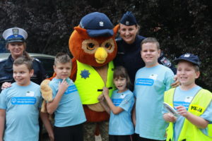 Grupa młodych sportowców pozująca z policjantkami maskotka policji.