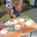 Przedszkolak wraz z wychowawcą malujący kropki paluszkami z wykorzystaniem farb.