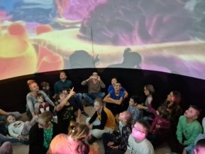 Grupa obserwująca projekcję w mobilnym planetarium.