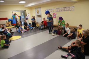 Przedszkolaki podczas zabawy muzyczno - ruchowej z clownem.
