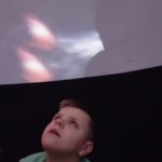 Uczeń obserwujący projekcję wmobilnym planetarium.