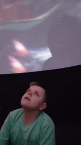 Uczeń obserwujący projekcję wmobilnym planetarium.