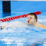 Chłopak płynący w basenie stylem dowolnym.