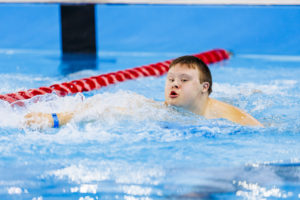 Chłopak płynący w basenie stylem dowolnym.