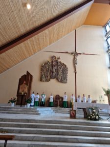 Ksiądz oraz ministranci na tle ołtarza w kościele.